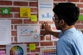 Young asian creative man reading and thinking about paper work ideas on office wall with concentration, working occupation Royalty Free Stock Photo