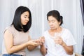 Asian daughter giving pills to old mother helping her mom taking medicine with glass of water