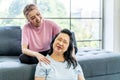 Young Asian daughter massages shoulder, relieves pain of elderly Asian mother while sitting on the sofa at home, Family concept. Royalty Free Stock Photo