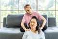 Young Asian daughter massages shoulder, relieves pain of elderly Asian mother while sitting on the sofa at home, Family concept. Royalty Free Stock Photo