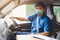 Young asian delivery man wearing protective face mask driving his van with packages on the front seat due to Coronavirus disease Royalty Free Stock Photo