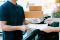 Young asian delivery staff holding the pen and documents submitting giving to the customer receiving the parcel at front house