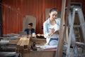 Young Asian designer furniture woman Carpenter uses a tape measure to measure chair on the workbench in woodcraft carpentry