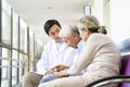 Young asian doctor talking to senior couple patients in hospital hallway Royalty Free Stock Photo