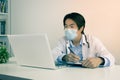 Asian Doctor and Stethoscope Wear Face Mask Write Experimental Results Report and Using Laptop Computer in Vintage Tone Royalty Free Stock Photo