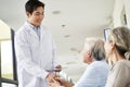 Young asian doctor shaking hands with senior patient