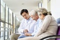 Young asian doctor talking to senior couple patients in hospital hallway Royalty Free Stock Photo