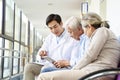 Young asian doctor talking to senior couple patients in hospital hallway Royalty Free Stock Photo