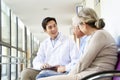 Young asian doctor talking to senior couple patients in hospital hallway Royalty Free Stock Photo