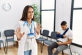 Young asian doctor woman at waiting room with a man with a broken arm disgusted expression, displeased and fearful doing disgust