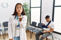 Young asian doctor woman at waiting room with a man with a broken arm looking at the camera blowing a kiss with hand on air being