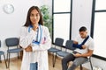 Young asian doctor woman at waiting room with a man with a broken arm looking confident at the camera with smile with crossed arms Royalty Free Stock Photo