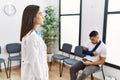 Young asian doctor woman at waiting room with a man with a broken arm looking to side, relax profile pose with natural face with Royalty Free Stock Photo