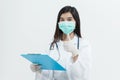 Young Asian doctor woman wearing doctor gown uniform coat , medical mask and stethoscope holding a clipboard looking happy