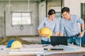 Young Asian engineer couple work together using notebook computer at building construction site. Civil engineering meeting concept