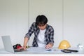 Young Asian engineer drawing construction project plans on plan paper on table in office Royalty Free Stock Photo