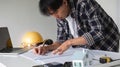Young Asian engineer drawing construction project plans on plan paper on table in office Royalty Free Stock Photo