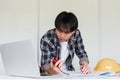Young Asian engineer drawing construction project plans on plan paper on table in office Royalty Free Stock Photo