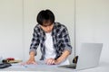 Young Asian engineer drawing construction project plans on plan paper on table in office Royalty Free Stock Photo