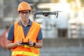 Young Asian engineer flying drone over construction site