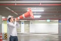 Young Asian engineer yelling though traffic safety cone in parking lot Royalty Free Stock Photo