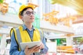 Young asian engineers are working on the construction site. Wear a yellow helmet safety and uniform staff. Hand holding smart