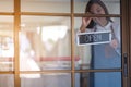 A young entrepreneur or a waitress hanging open sign on the shop front door