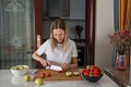 Young caucasian woman cooking fresh fruit and vegetable salad on table. Person preparing healthy yummy eating lunch in Royalty Free Stock Photo