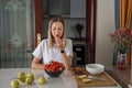 Young caucasian woman cooking fresh fruit and vegetable salad on table. Person preparing healthy yummy eating lunch in Royalty Free Stock Photo