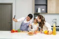 Young Asian family are preparing salad in the kitchen and father take a photo selfie by phone. Excited smiling and felling happy.