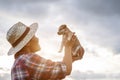 Young Asian farmer playing with his brown small pup in the evening after work