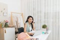 A young Asian fashion designer on her atelier making a phone call Royalty Free Stock Photo