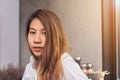 Young Asian female barista relaxing by sitting in her own coffee shop and be warmed by the warm sunshine in late of afternoon. Royalty Free Stock Photo