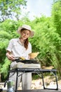 Young Asian female at the campground, preparing barbecue picnic party food, grilling a steak Royalty Free Stock Photo