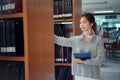 Young asian female college student taking book from shelf in library Royalty Free Stock Photo