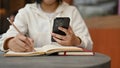 A young Asian female college student using her smartphone while doing her homework Royalty Free Stock Photo