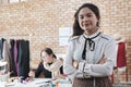 Young Asian female designer stands and arms crossed, working in tailor studio