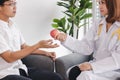 Young Asian female doctor giving red apple to patient for encouragement and empathy Royalty Free Stock Photo