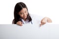 Young Asian female doctor point and look down to blank sign. Royalty Free Stock Photo