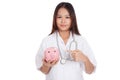 Young Asian female doctor point to a pig bank coin Royalty Free Stock Photo