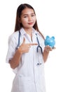 Young Asian female doctor point to a pig bank coin. Royalty Free Stock Photo