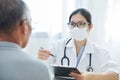 Asian Female Doctor talking to senior man patient. Royalty Free Stock Photo