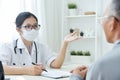 Asian Female Doctor talking to senior man patient. Royalty Free Stock Photo