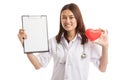 Young Asian female doctor with red heart and blank clipboard. Royalty Free Stock Photo