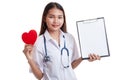 Young Asian female doctor with red heart and blank clipboard. Royalty Free Stock Photo