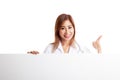 Young Asian female doctor standing behind blank white billboard Royalty Free Stock Photo