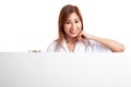 Young Asian female doctor standing behind blank white billboard Royalty Free Stock Photo