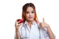 Young Asian female doctor thumbs up with apple. Royalty Free Stock Photo