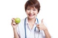 Young Asian female doctor thumbs up with apple. Royalty Free Stock Photo