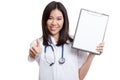 Young Asian female doctor thumbs up with a blank clipboard.